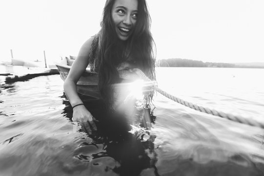 Brunette woman leans into the water on the bow of the boat