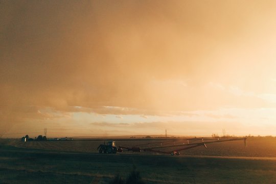 A tractor leaving the field at sunset