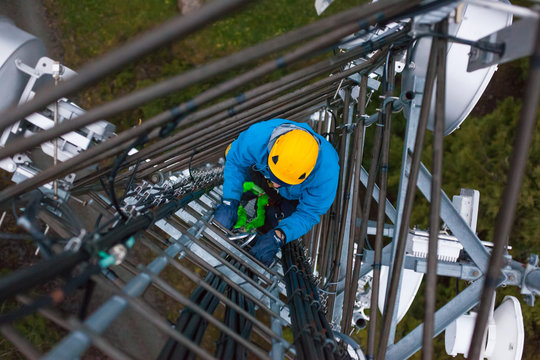 Working at heights, technician climbs up on a communications tower