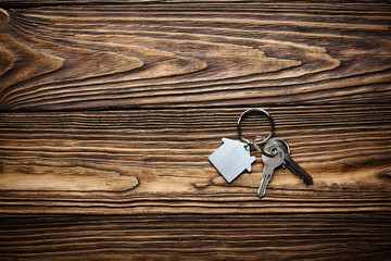Symbol of house with silver key on wooden background