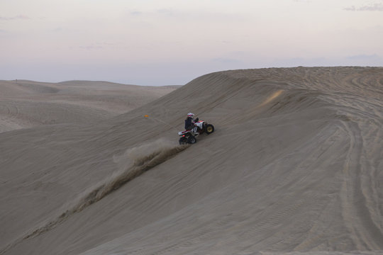 Woman riding a quad up a sand dune