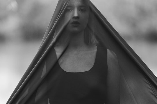 Young woman hiding behind a veil