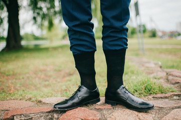 Unrecognizable man in wedding suit standing outdoor with socks put on trousers. Groom in black...