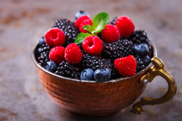 Berry Fresh in a copper cup on the Metal Background. Blackberries,Bramble,raspberry with mint.Food or Healthy diet concept.Super Food.Vegetarian.selective focus.
