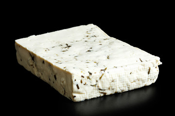 Single block of natural tofu with herbs isolated on black.