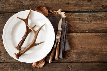 Deer antlers on plate with cutlery against table