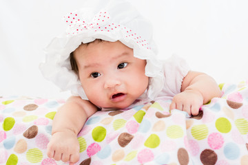 Portrait of a little adorable infant baby girl lying on the tummy on the pillow with head band