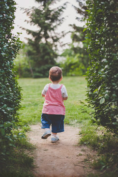 Back of a toddler girl walking confidently photographed from behind.
