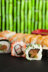 Sushi rolls on black table and green bamboo background