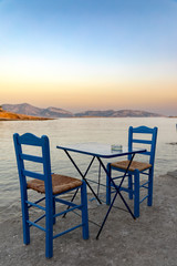 Klassisch, griechische Stühle und Tisch am Meer bei Sonnenuntergang, Kykladen, Griechenland