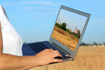Kobieta z laptopem w krajobrazie wiejskim. - obrazy, fototapety, plakaty