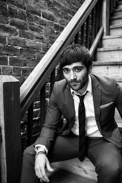 Man in suit sitting on stairs looking at camera