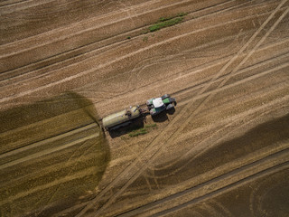 Fototapeta premium aerial view of a tractor with a trailer fertilizes a freshly plowed agriculural field with manure in germany