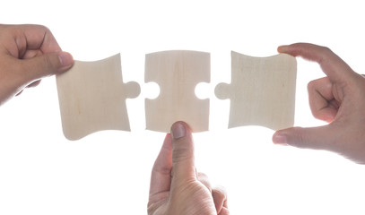 Hand holding jigsaw puzzles isolated over white,wooden puzzle.
