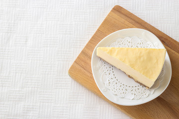Slice cheesecake on wooden cutting board White background Selective focus Copy space
