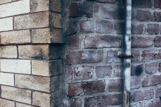 Drain pipe outside of old brick building, close up