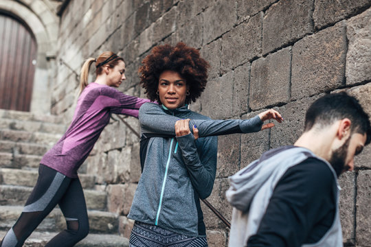 Young multiethnic runners doing stretching exercises on steps.