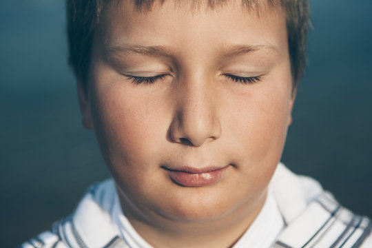 Portrait of ten year old boy with eyes closed, close up