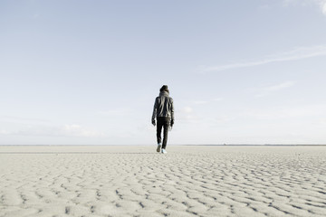Hip young guy walking alone on the beach.