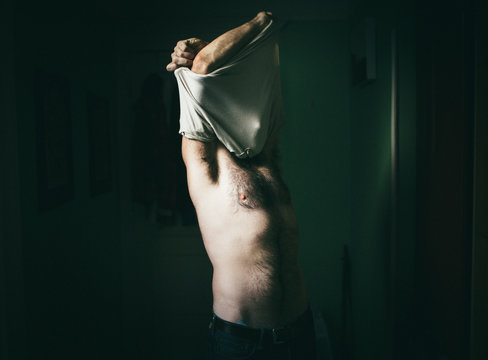 A man undresses in his Brooklyn apartment