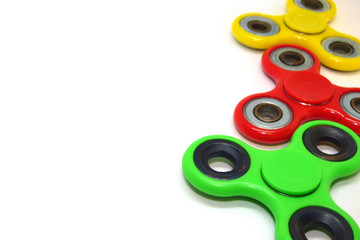 Bright colored fidget finger spinners on white background. Red, green and yellow stress relieving...