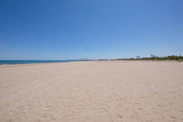 landscape beach in Grao of Castellon, named PIne or Pinar, in Valencia, Spain, Europe. Blue clear sky, Mediterranean Sea and harbour in the horizon

