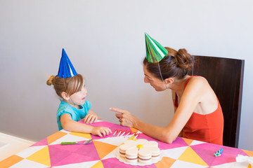 woman with orange sleeveless top talking to three years old blonde child blue shirt, at birthday...