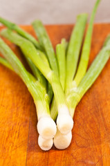 Organic, local, fresh green onions on a wood cutting board