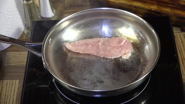 Adding boneless chicken beast fillets to a frying pan
