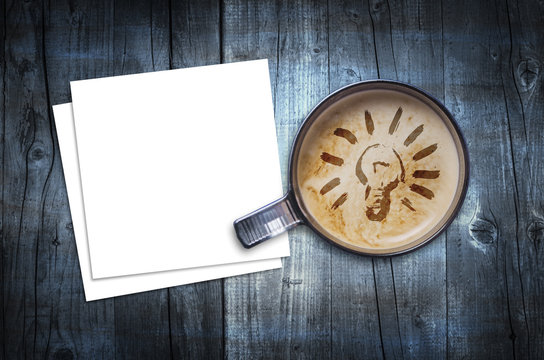 Fresh idea. Cup of fresh espresso with bulb sign and blank note paper, view from above.