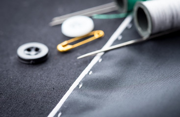 needles, cotton reels and buttons on black fabric