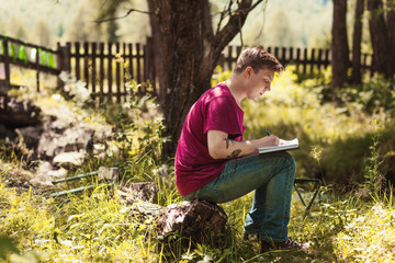 Young Man reading book and writing notes on background.