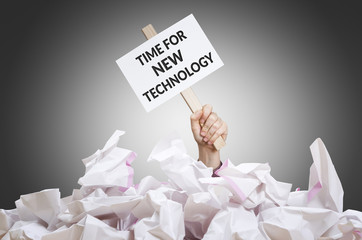 Time for new technology placard in hand with crumpled paper pile.