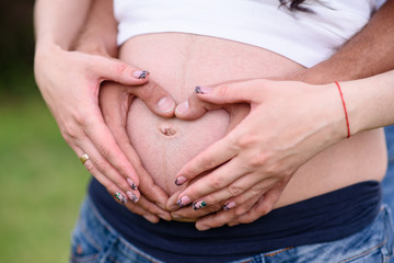 Hands on the stomach of a pregnant girl.