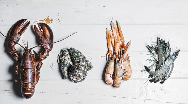 Lobster,oyster,langoustine and shrimp on a wooden surface ready to be prepared for cooking.