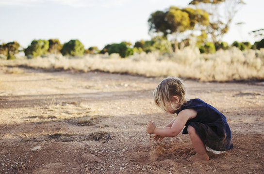 Little girl playing with red dirt