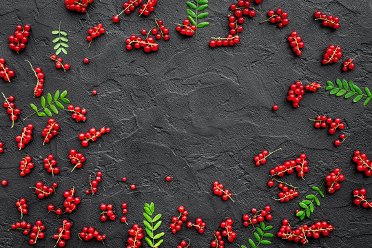 Berry frame. Red currant and leaves on black table background top view copyspace