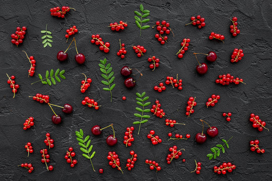 Berry pattern. Red currant, cherry and leaves on black table background top view