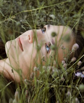 Girl is laying in the grass and flowers on the spring meadow