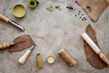 Leather craft. Tanner's tools on grey stone background top view copyspace