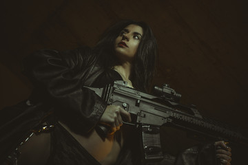 Protection, Beautiful brunette girl armed and dangerous with a gun in her hand and dressed in black leather