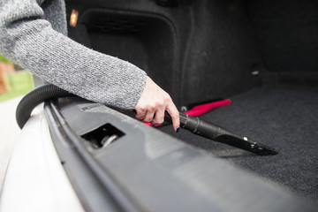 Young woman hands vacuuming car trunk of the dust