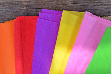 Closeup to colorful crepe paper on wooden background. Crafts, handicrafts.