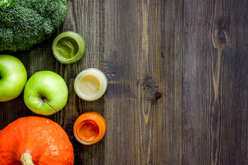 Fototapeta na wymiar Preparing baby food. Broccoli, pumpkin, apple puree on dark wooden table background top view copyspace