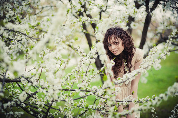 Curly brunette girl standing in blossoming trees