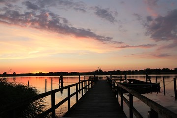 Fototapeta na wymiar malerischer Abendhimmel an einem Steg mit Boot kurz nach Sonnenuntergang