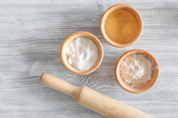Put the dough. Flour, salt, mik, oil, rolling pin on light wooden table background top view copyspace