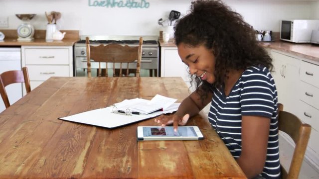 Teenage Girl With Digital Tablet Revising For Exam At Home