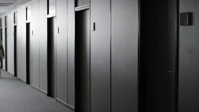 Office employee walking through corridor and turning the lights off