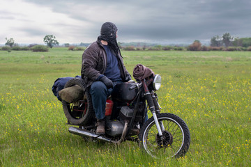 A post apocalyptic man on motorcycle in a meadow